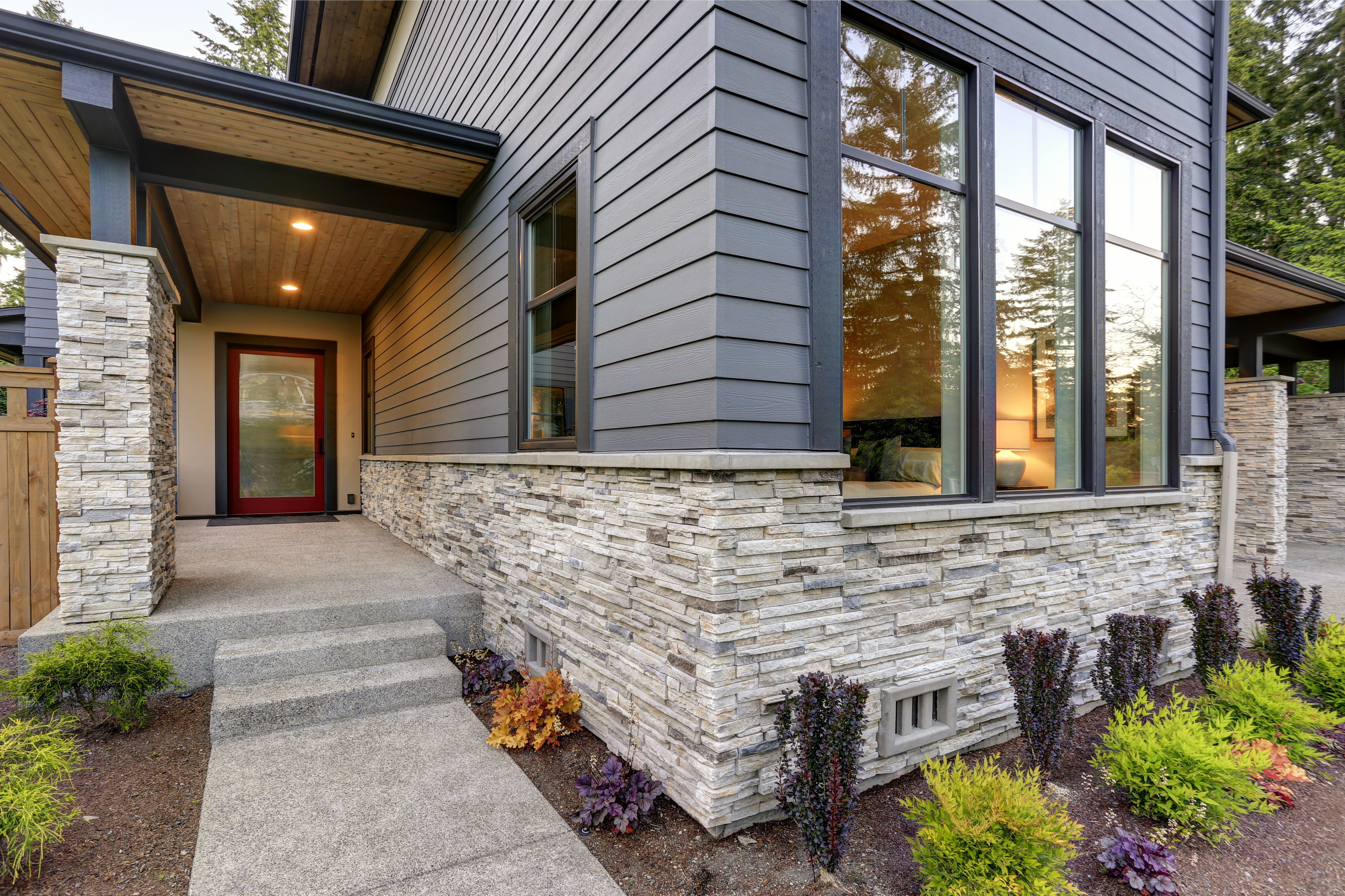 Luxurious new home with curb appeal. Trendy grey two-story exterior in Bellevue with large picture windows stone siding covered porch and concrete pathway. New Zealand
